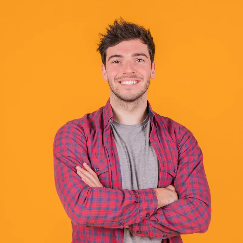 portrait-smiling-young-man-with-his-arm-crossed-standing-against-orange-backdrop